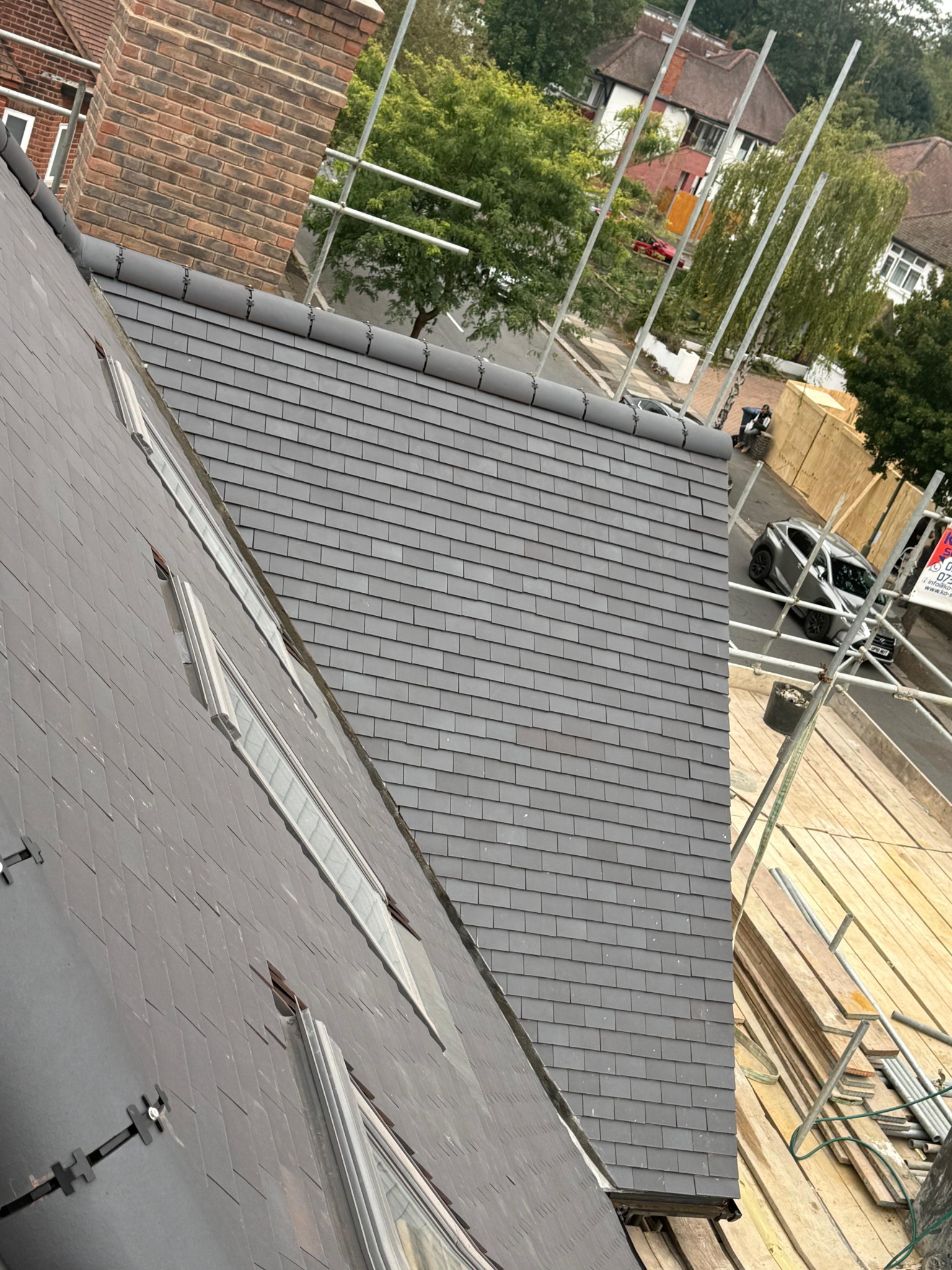 Tiled gable roof with ridge tiles beside a brick wall