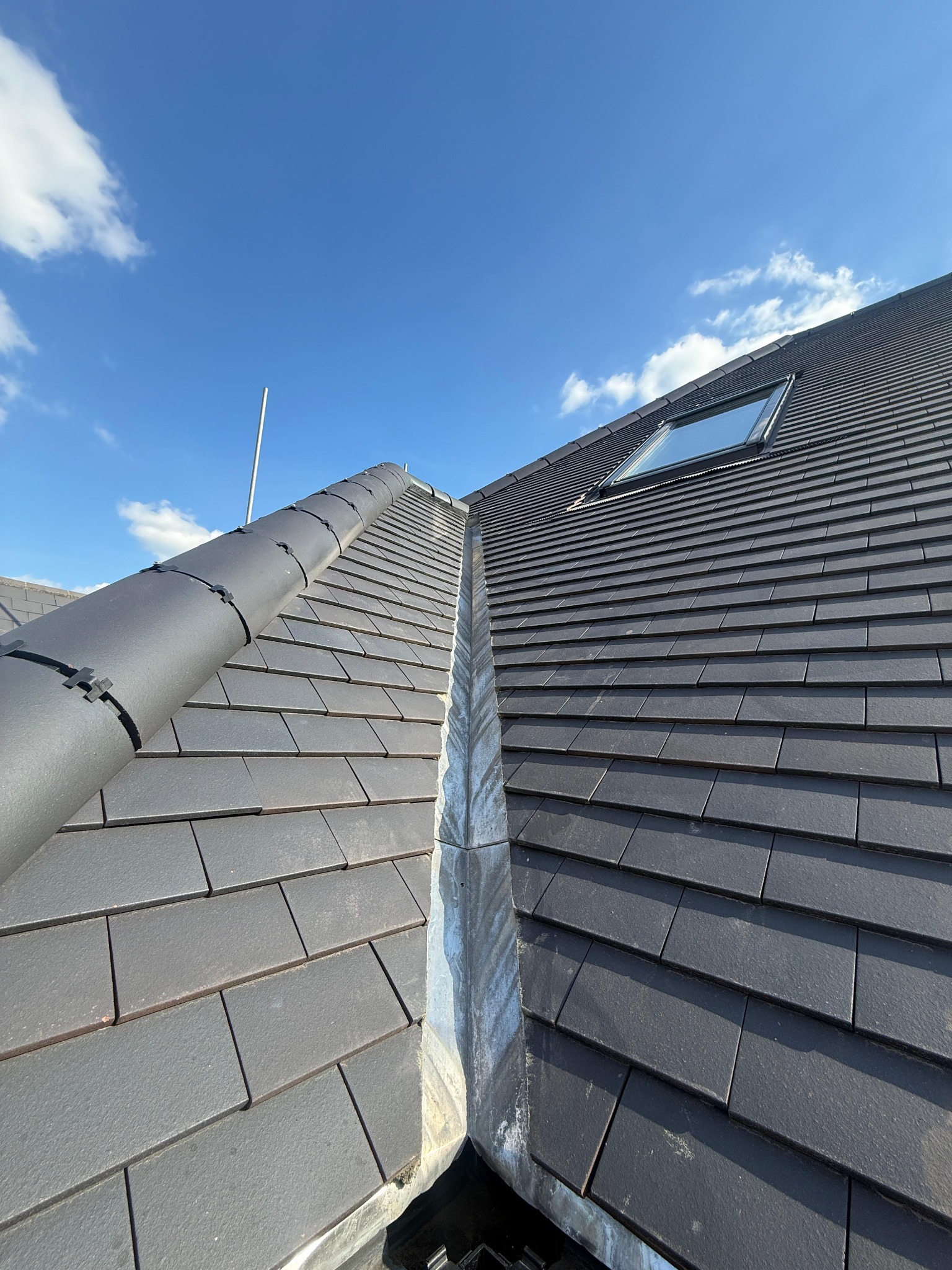 Junction between two tiled roof slopes with a metal-lined valley