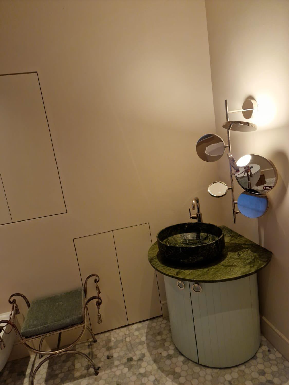 Rounded painted vanity cabinet beneath a green stone basin and worktop
