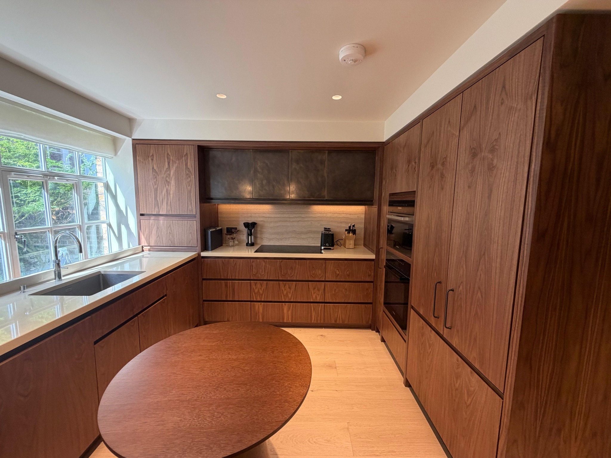 Timber kitchen with continuous grain cabinetry, pale worktops and integrated appliances